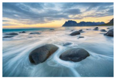 Solnedgang over strand med steiner